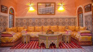 Una habitación al estilo marroquí con un conjunto de sofás, paredes con diseños y luces decorativas.