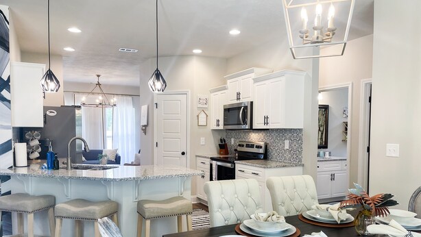 A modern kitchen with a central island, bar stools, a dining table set for six, and a chandelier. - Cheerful spacious home-5 min to Bruce's Field/Downtown (Aiken)