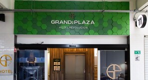 The entrance to Grand Plaza Hotel Revolucion with a green hexagonal pattern wall, a wooden door, and a sign indicating room availability. - Hotel Grand One Plaza (Tijuana)
