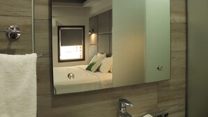A modern bathroom with a large mirror, a sink, and a towel rack. - Hotel Grand One Plaza (Tijuana)
