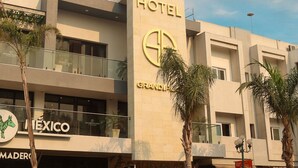 A hotel with a modern facade, a prominent 'HOTEL' sign, and the name 'GRANDI PLAZA' visible. - Hotel Grand One Plaza (Tijuana)