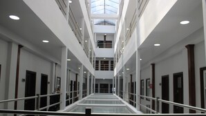 A modern hotel corridor with glass railings, multiple floors, and a central skylight. - Hotel Grand One Plaza (Tijuana)