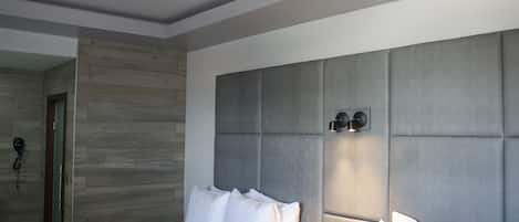 A modern hotel room with a large bed, a bedside table, and a built-in headboard.
