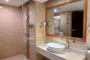 A bathroom with a glass-enclosed shower, a large mirror, and a white sink. - Vienna Hotel (Fengshan) (Fengshan)