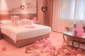 A bedroom with a bed, a glass table, and balloons. - Vienna Hotel (Fengshan) (Fengshan)