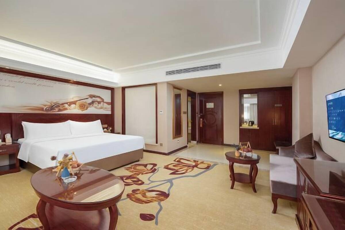 A hotel room with a bed, a TV, a desk, and a chair.