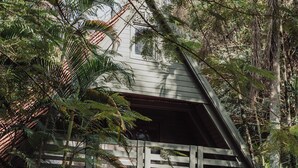 Ein Haus mit geneigtem Dach, einem Holzbalkon und einem Steinfundament.