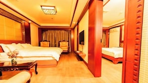 Een hotelkamer met twee bedden, een houten vloer, een televisie en een spiegel.