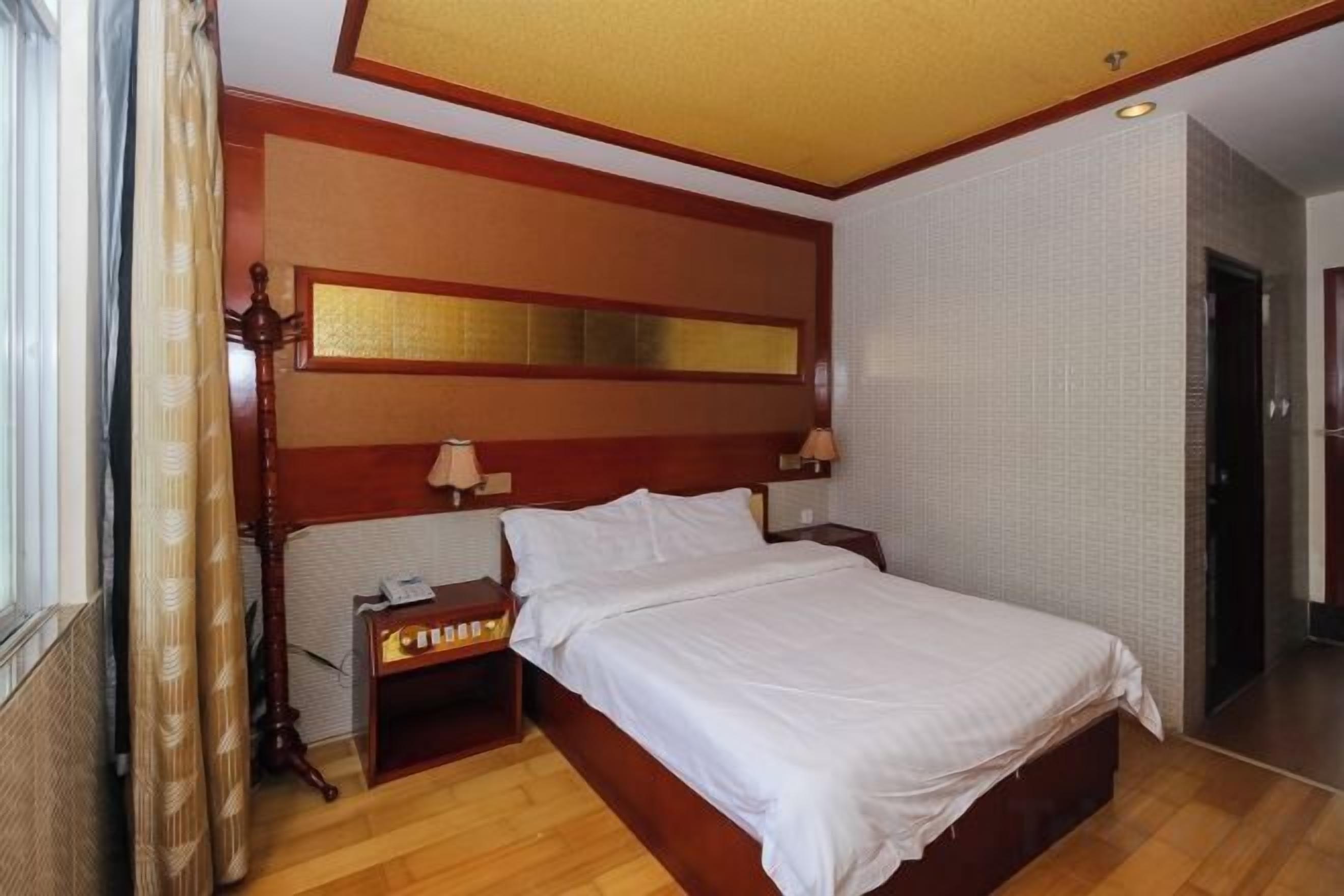 A hotel room with a large bed, wooden headboard, bedside tables, and a nightstand.