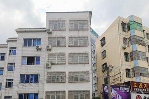 Un edificio de varios pisos con una cuadrícula de ventanas y unidades de aire acondicionado.