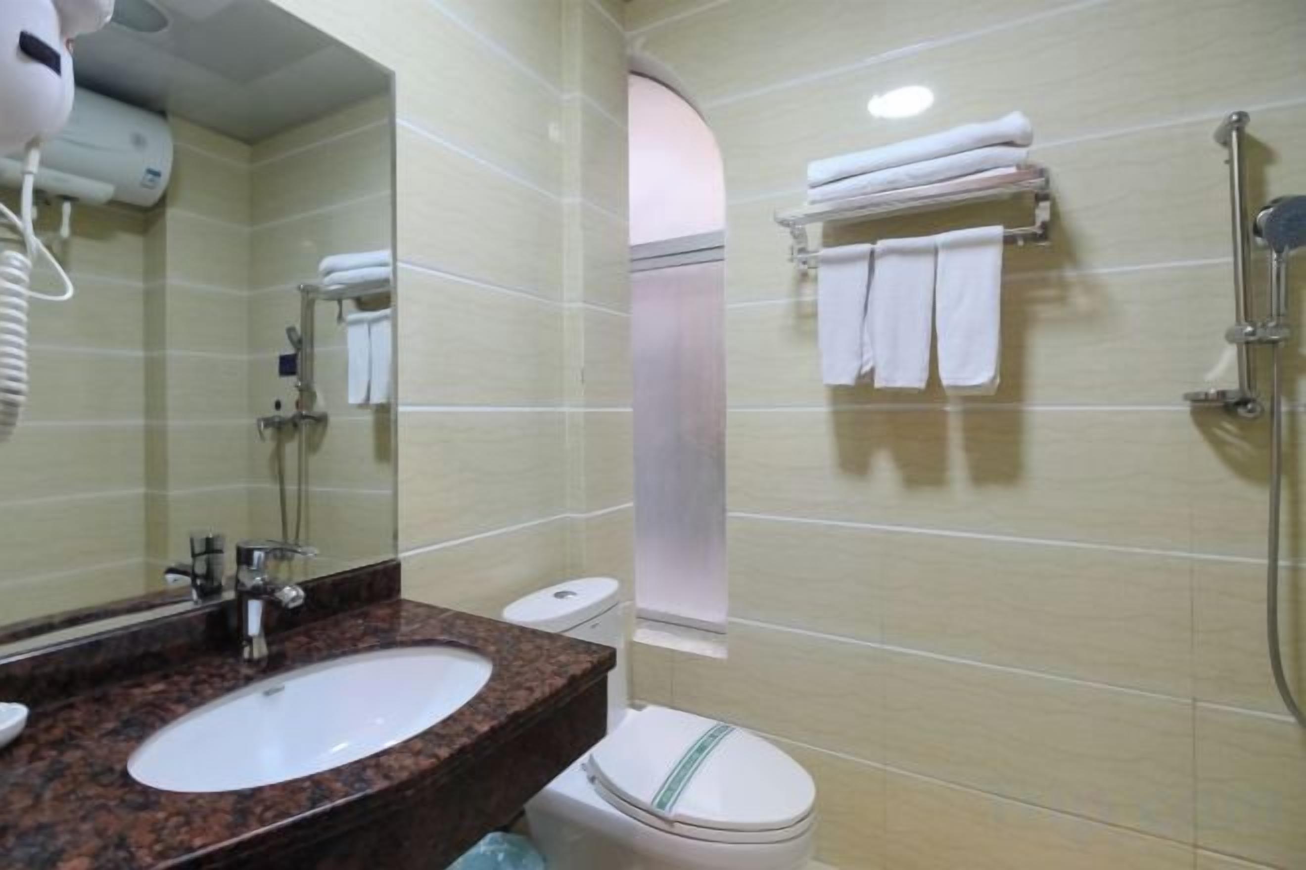 A hotel bathroom with a sink, toilet, and shower.