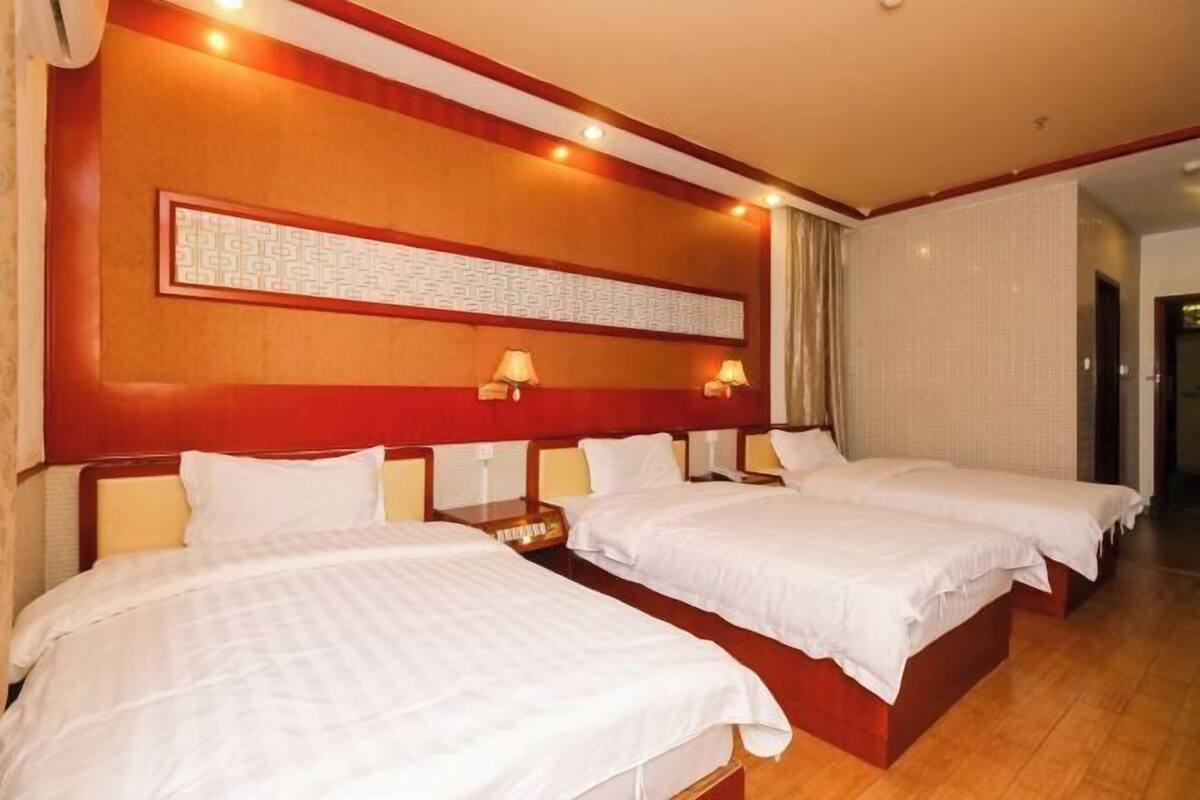 Habitación de hotel con dos camas, un cabecero de madera, una obra de arte colgada en la pared y dos lámparas de noche.