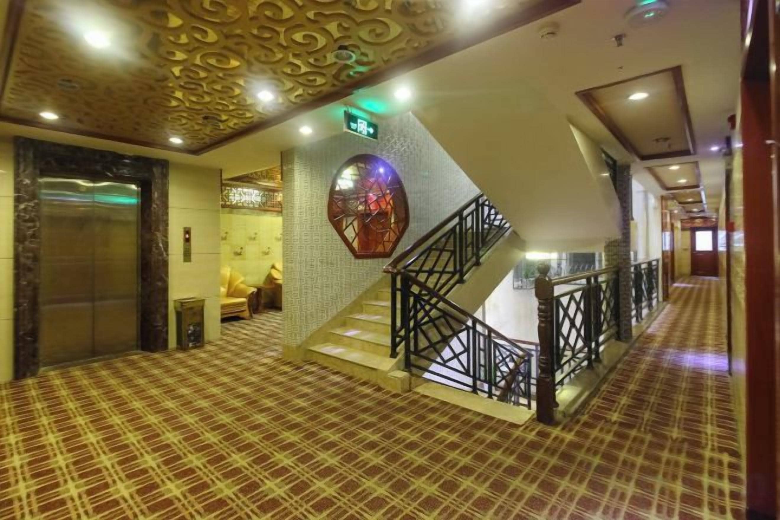 A hotel lobby with a check-in desk, a staircase, and a patterned floor.