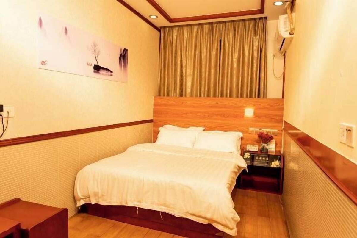 Una habitación de hotel con cama, mesita de noche y teléfono en la pared.