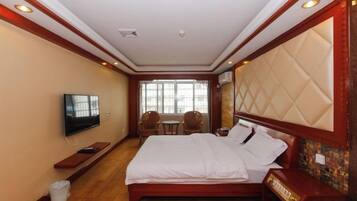 A hotel room with a large bed, a television, a small table, and a window with a view.