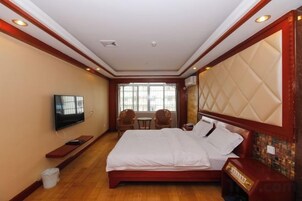 Habitación de hotel con una cama grande, televisión, una mesita y ventana con vistas.