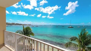 A balcony with a view of a turquoise sea, palm trees, and boats. - Encanto- 2 Bedroom Beachfront Condo - Simpson Bay! (Simpson Bay)