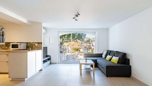 A modern living room with a sofa, a coffee table, and a kitchen area with a microwave. - Lower villa refurbished, air conditioning and terrace with sea view (ST MANDRIER SUR MER)