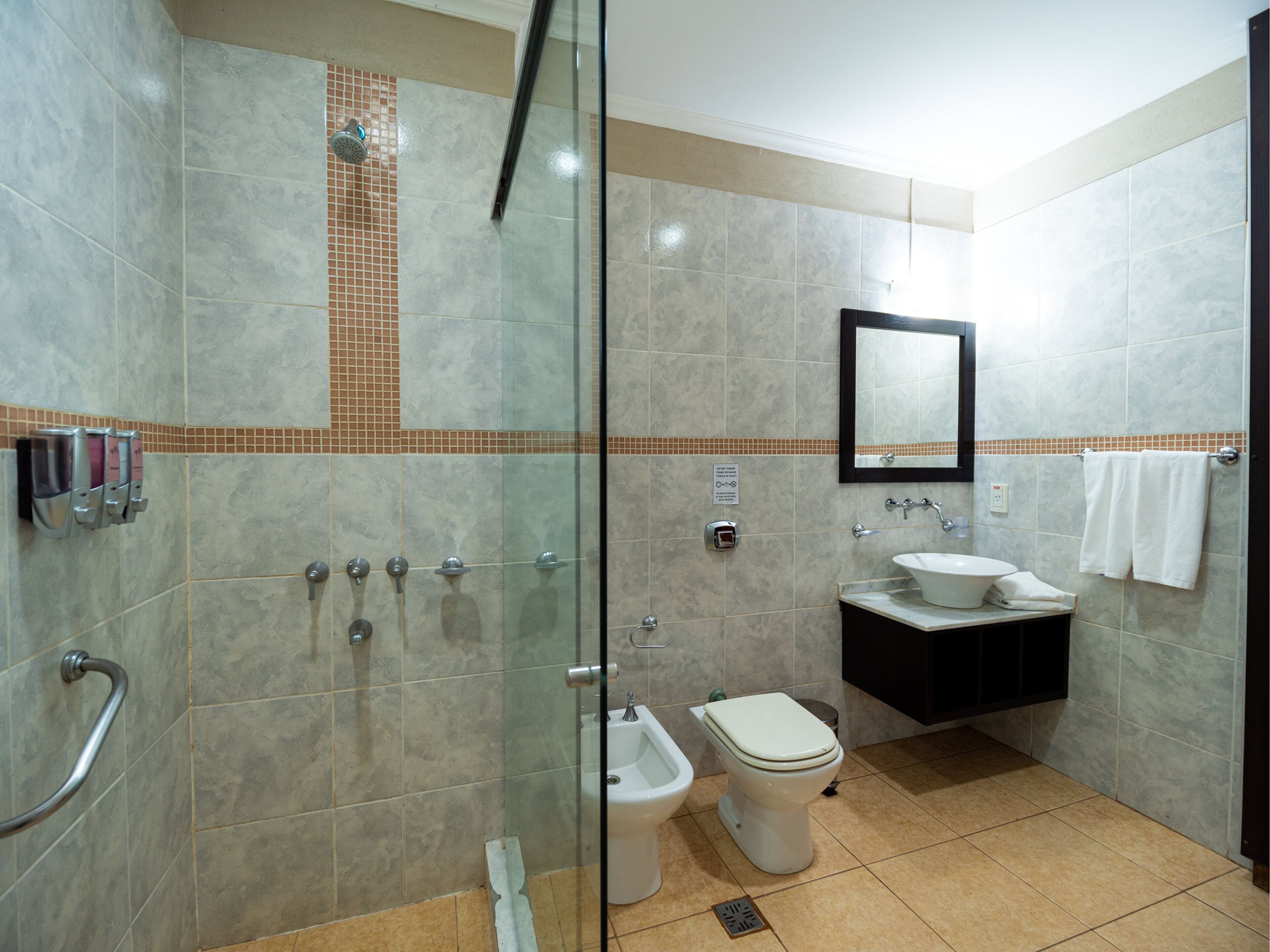 A modern bathroom with a glass shower enclosure, a bidet, a sink, and a toilet.