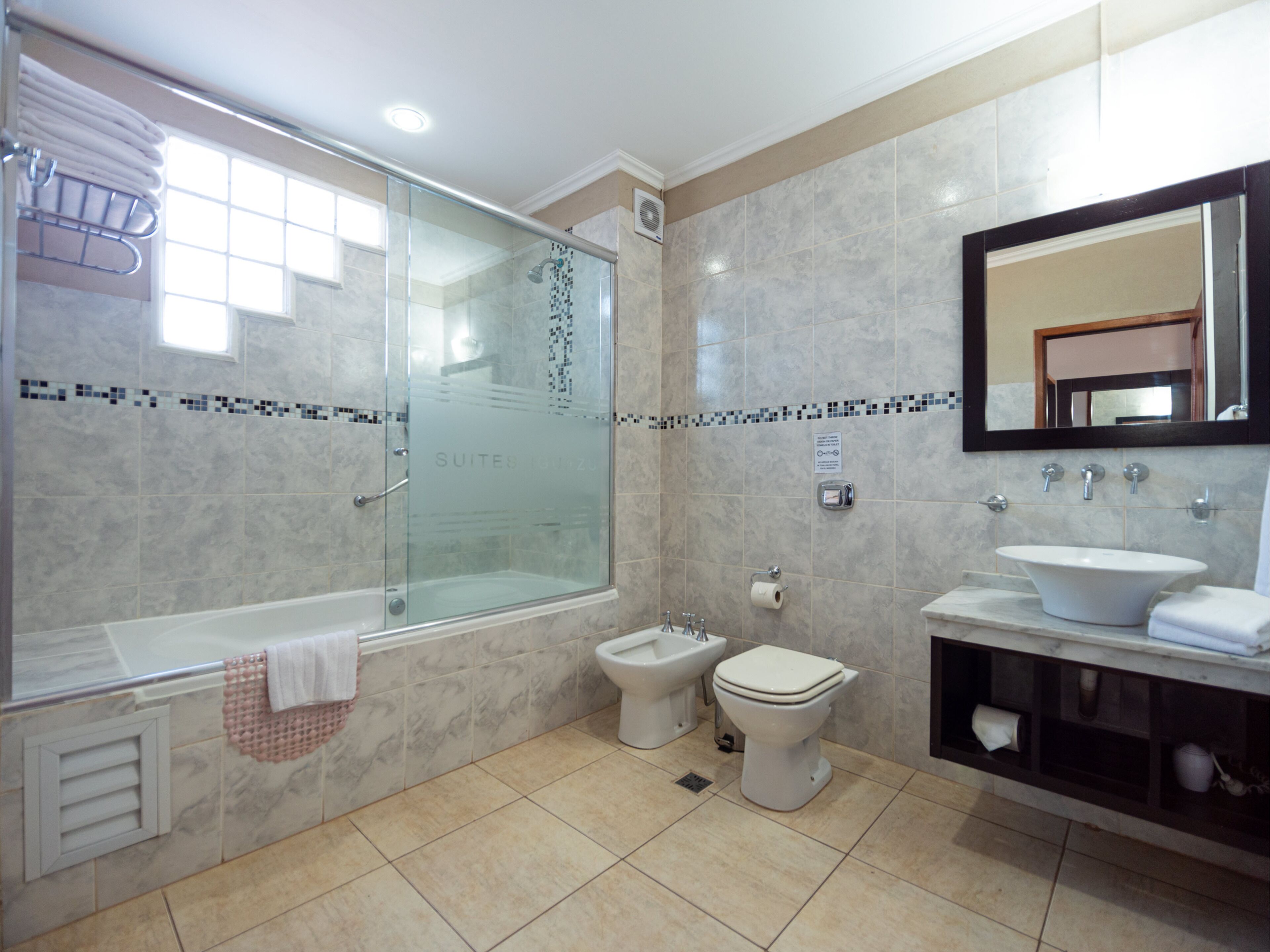 A modern bathroom with a glass-enclosed shower, a separate toilet, and a vanity with a sink and mirror.