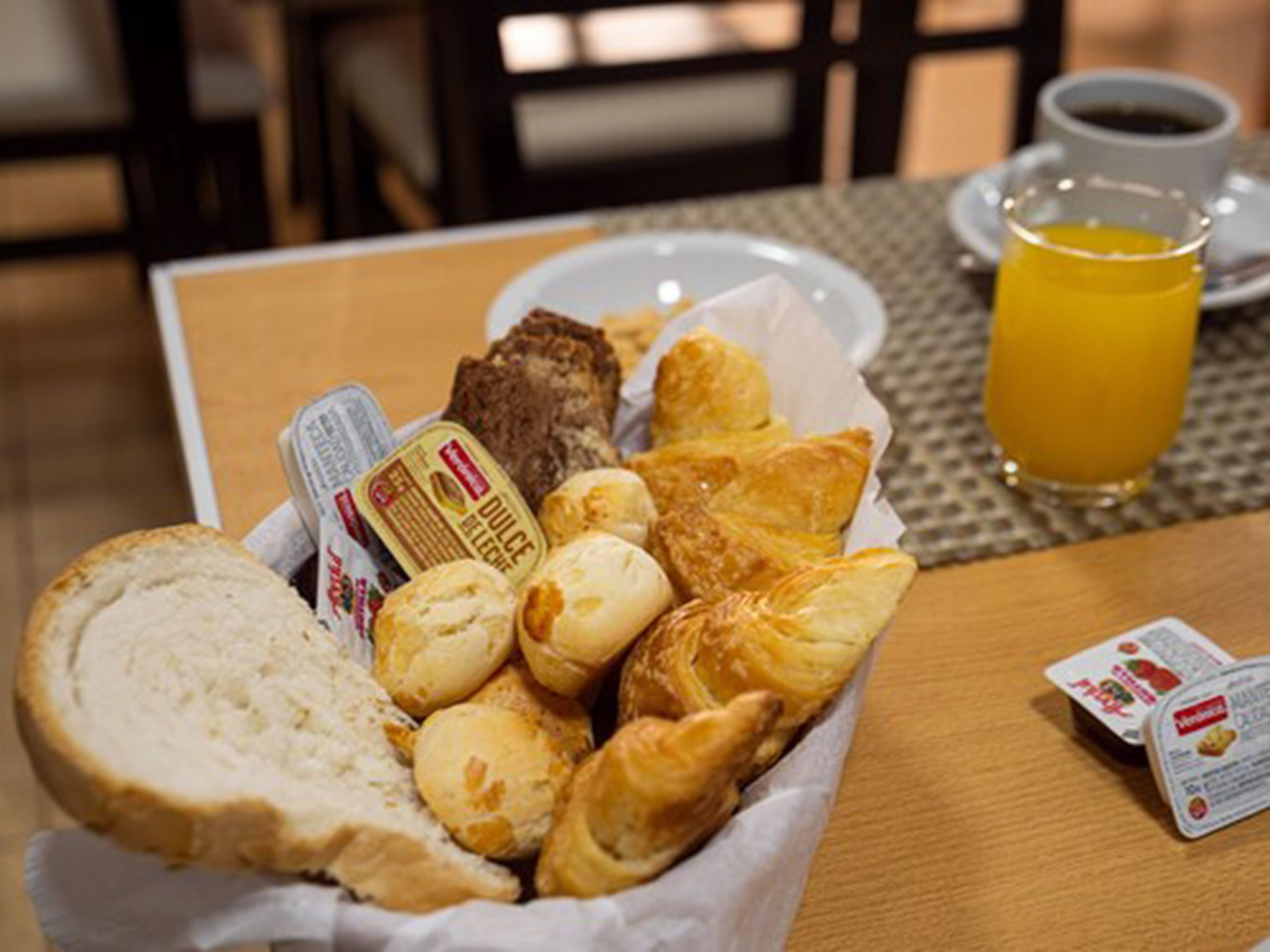 Un plateau de petit-déjeuner avec du pain, des viennoiseries et une boisson.