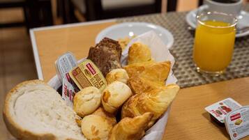 Un plateau de petit-déjeuner avec du pain, des viennoiseries et une boisson.