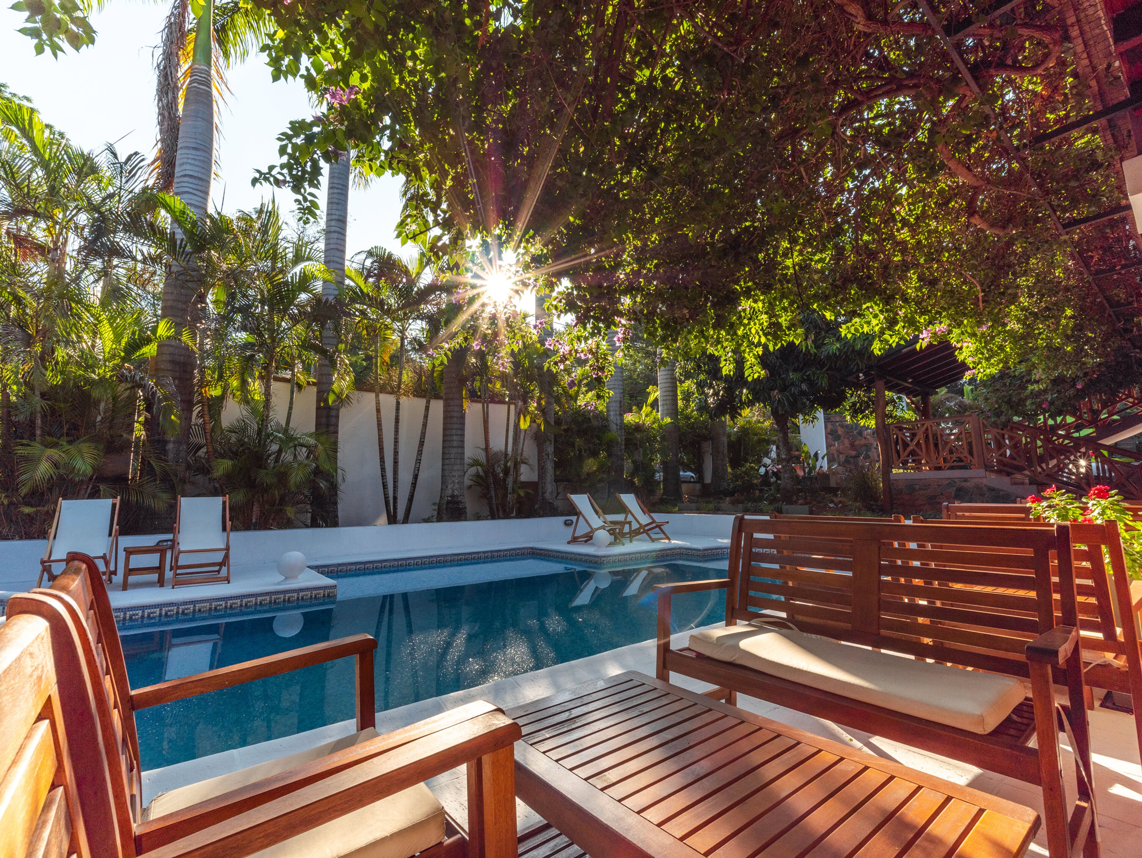 Área de piscina com espreguiçadeiras de madeira e uma piscina pequena.