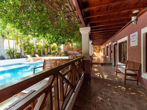 A covered pool area with wooden benches and a view of the pool. - Palma Real Posada (Puerto Iguazú)