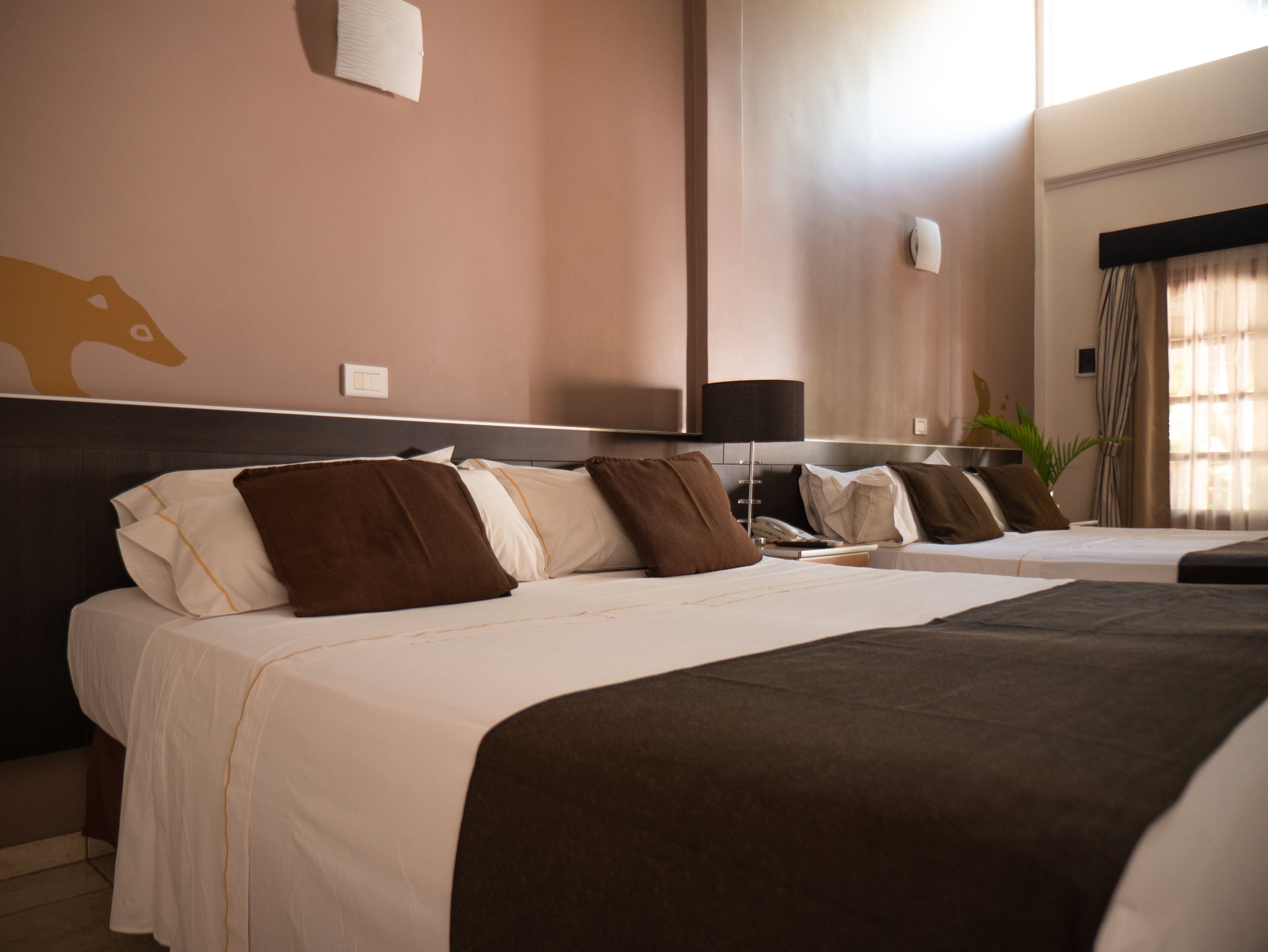Een hotelkamer met twee bedden, een grote wandklok en een plant.