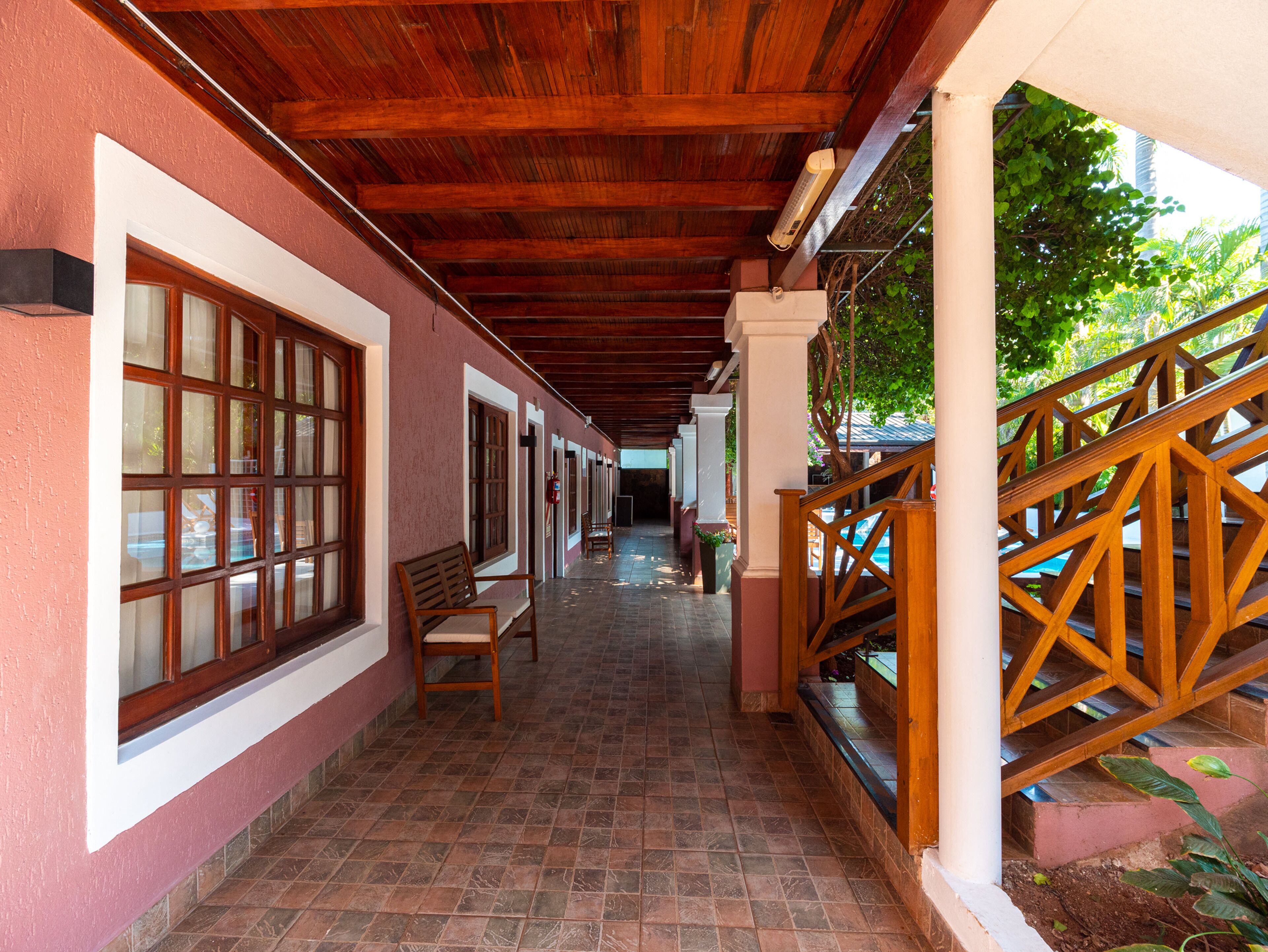 A corridor with wooden flooring, large windows, and a wooden railing.