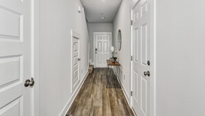 A hallway with white walls, wooden flooring, and white doors. - LUXURY TOWNHOME NEAR DOWNTOWN AND PENSACOLA BEACH (Pensacola)