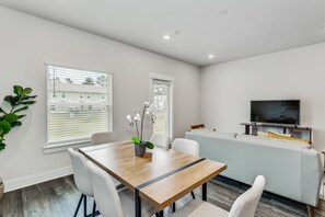 A modern living room with a dining table, chairs, a sofa, and a TV. - LUXURY TOWNHOME NEAR DOWNTOWN AND PENSACOLA BEACH (Pensacola)
