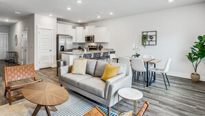 A modern living room with a sofa, coffee table, and dining area. - LUXURY TOWNHOME NEAR DOWNTOWN AND PENSACOLA BEACH (Pensacola)