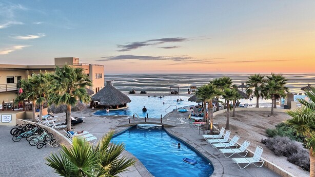 A pool area with lounge chairs, a small pool, and a beach view. - Beach Front House - EV charging included (Son.)