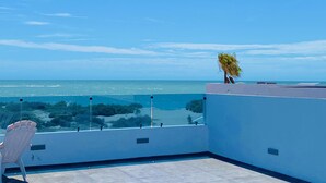 A balcony with a clear view of the sea, a chair, and a potted plant. - Beach Front House - EV charging included (Son.)