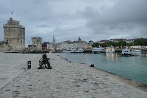 A waterfront promenade with a historic tower, boats docked, and a cobblestone path.