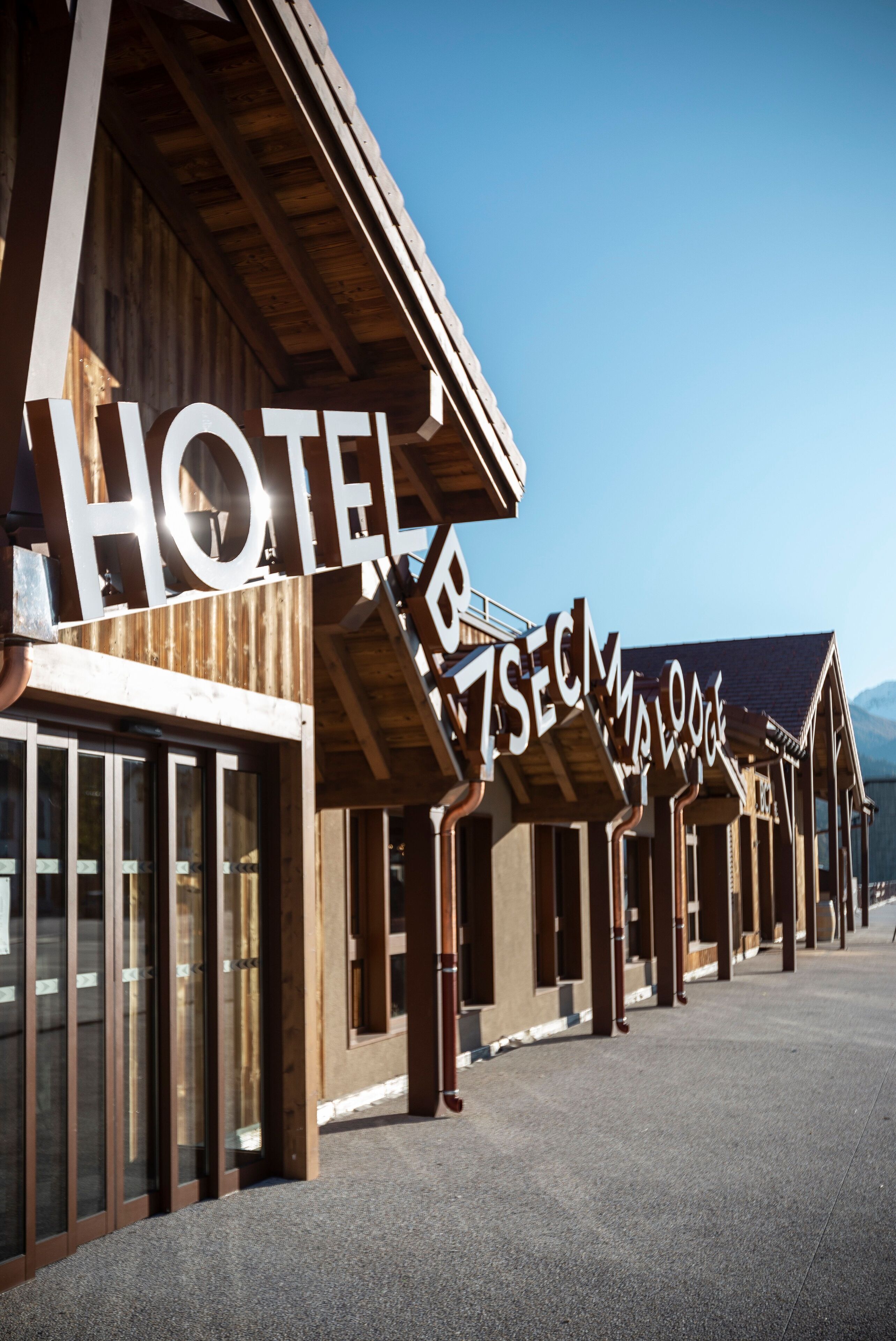 A row of wooden buildings with large signs indicating a hotel and a ski lodge.