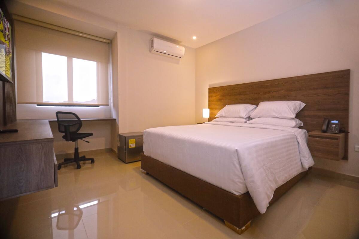 Une chambre d’hôtel moderne, dotée d’un grand lit, d’un bureau et d’une chaise.