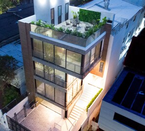 A modern multi-story building with a rooftop garden, large windows, and a staircase leading to the entrance. - Edificio Casa Tabor (Barranquilla)