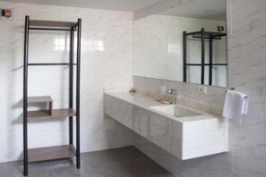 Une salle de bain moderne avec un lavabo en marbre, un miroir et une étagère en métal.