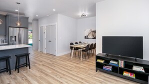 Eine moderne Küche mit grauen Schränken, einem integrierten Kühlschrank und einem Essbereich mit Tisch und Stühlen.