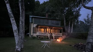 A two-story house with a covered porch and a fire pit in the yard.