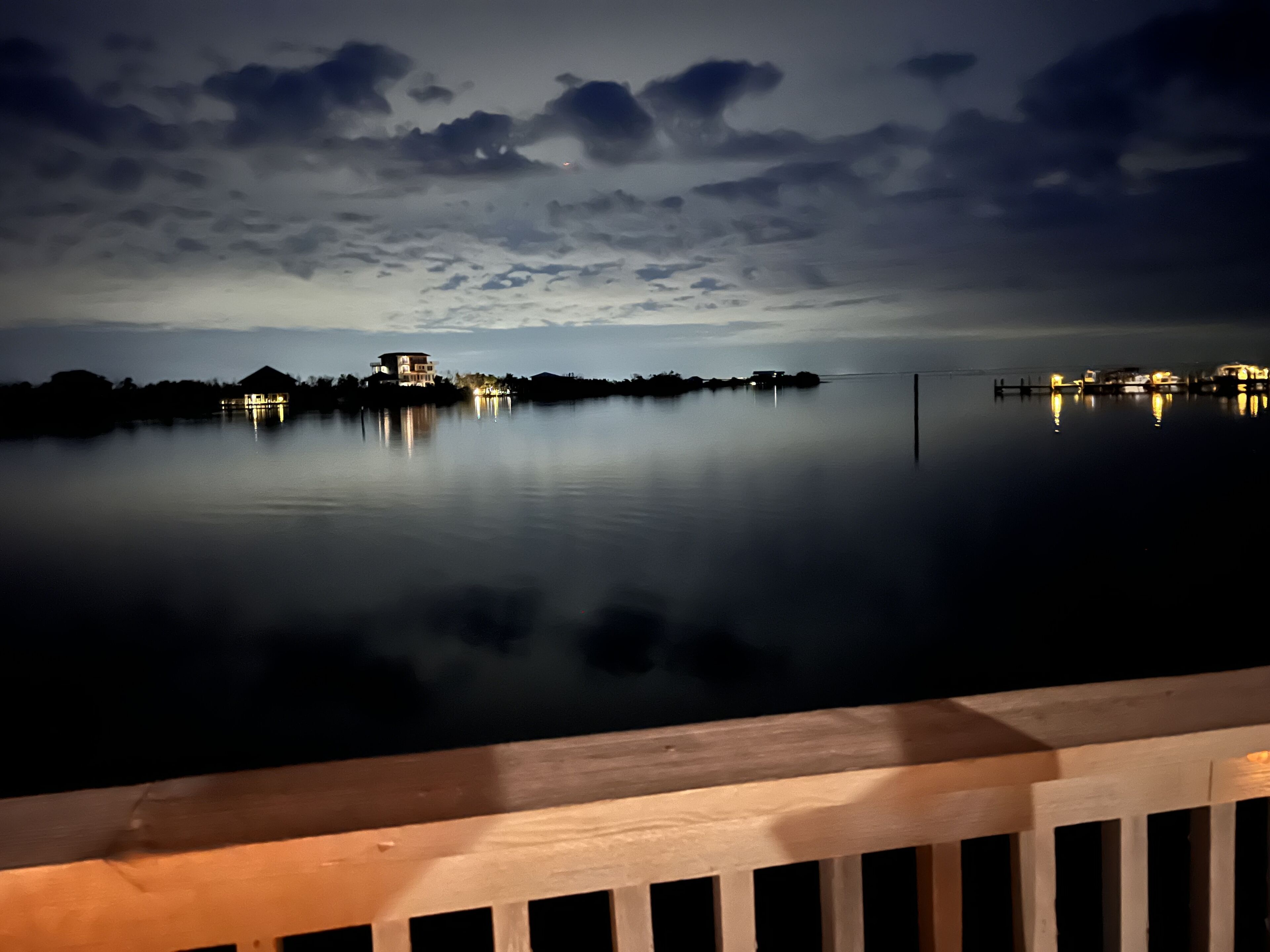 A calm lake at dusk with a house reflecting on the water.