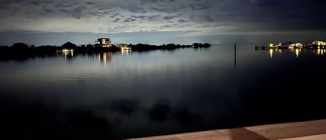 A calm lake at dusk with a house reflecting on the water.