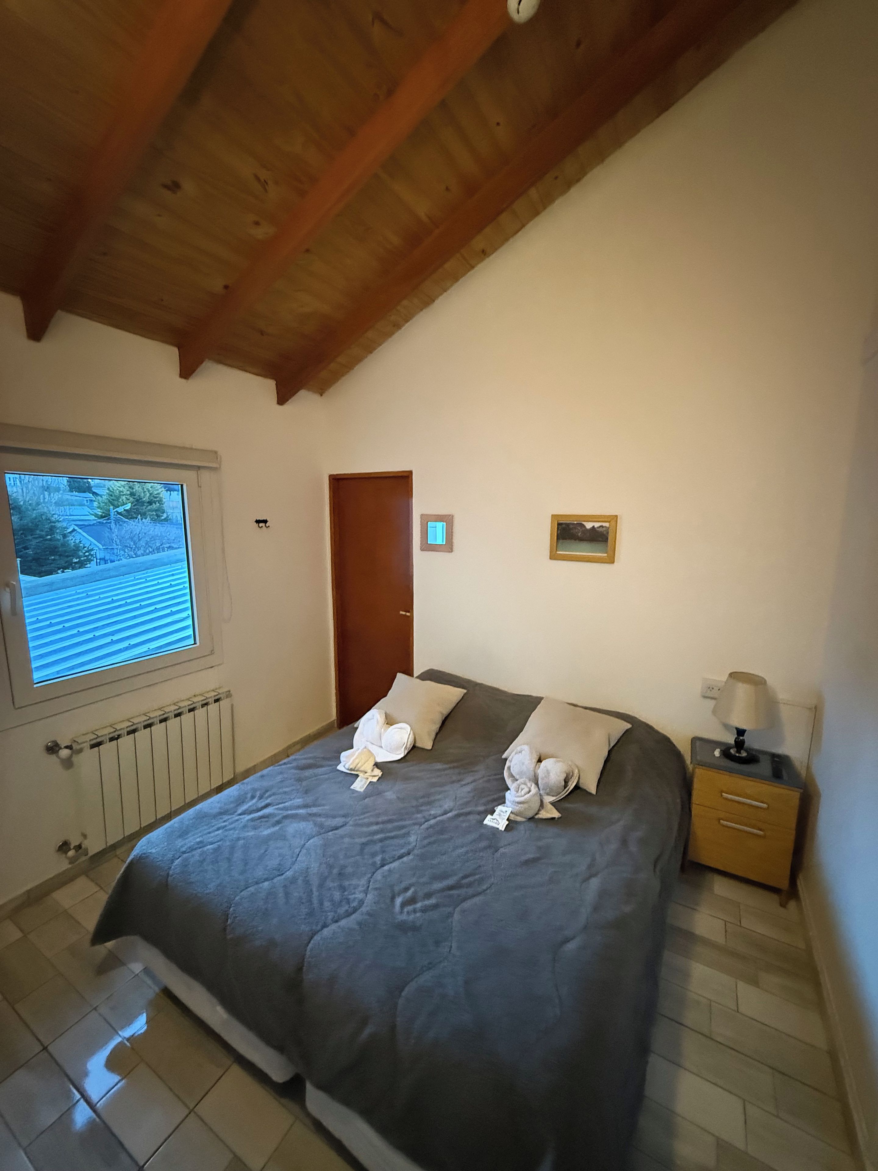 A bedroom with a bed, a nightstand, a window, and a door.