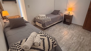 Una habitación con dos camas, televisión y una mesita de noche con lámpara.