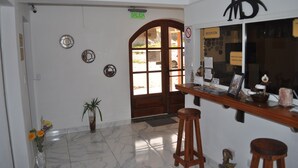 Zona de recepción con mostrador de madera, un cartel que indica 'SALIDA' y una ventanilla de recepción.