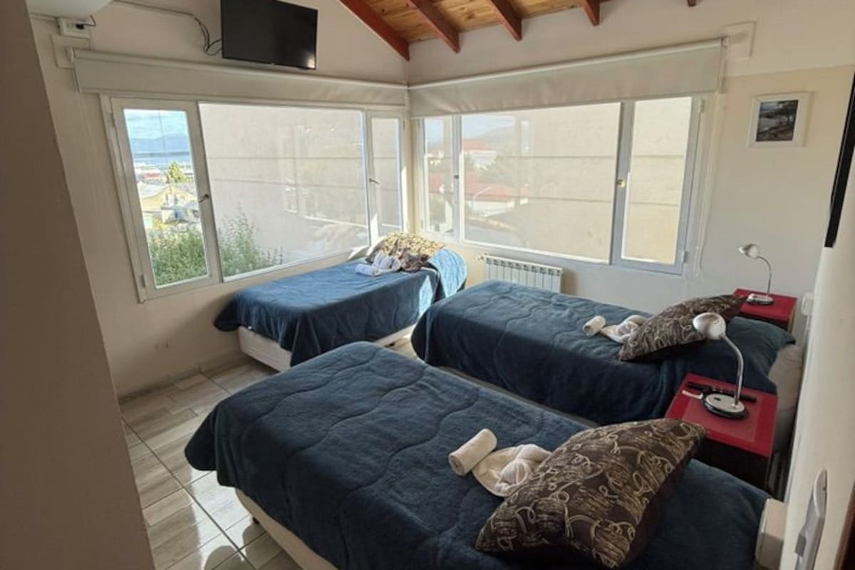 Une chambre avec deux lits, une télévision et une fenêtre donnant sur un beau paysage.