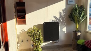 Una habitación iluminada por el sol con techo de madera, una pizarra, una planta en maceta y una pequeña estantería con una planta.