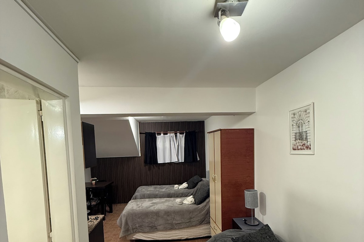 Une chambre avec deux lits, une armoire, un bureau et une petite table.